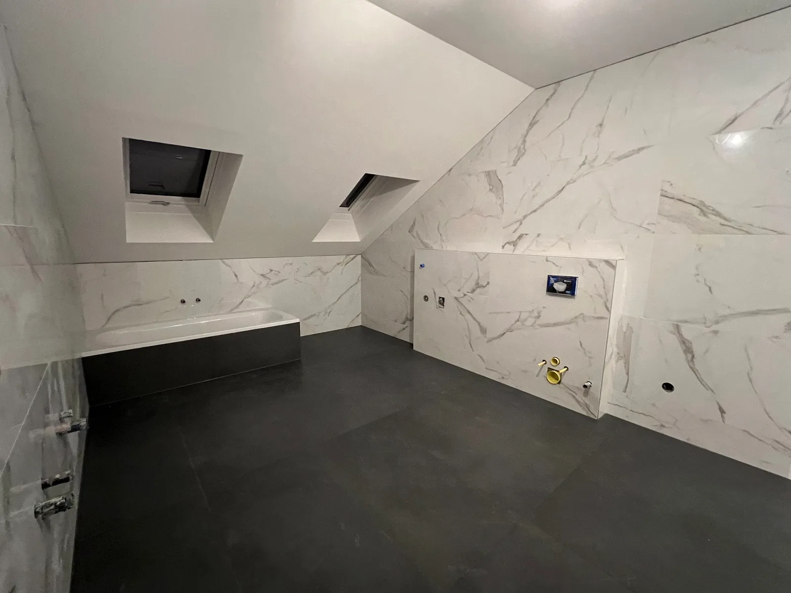 Dachgeschoss mit großformatigen Wandfliesen in heller Marmoroptik und dunklem Fliesenboden